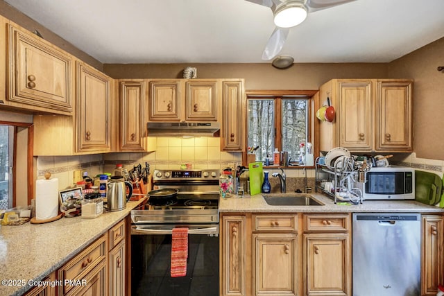 kitchen featuring appliances with stainless steel finishes, sink, backsplash, ceiling fan, and light stone countertops