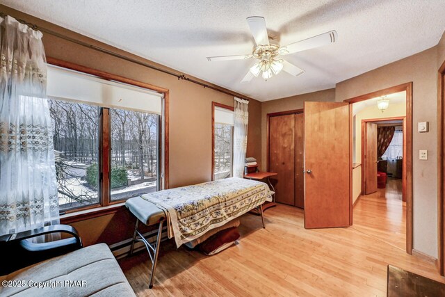 bedroom featuring ceiling fan, a textured ceiling, and light hardwood / wood-style flooring