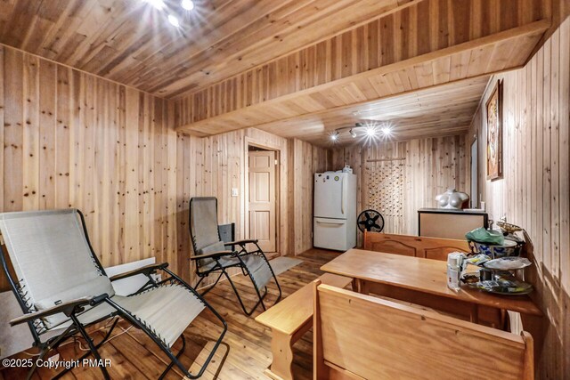 sitting room with wooden ceiling, wood walls, and light wood-type flooring