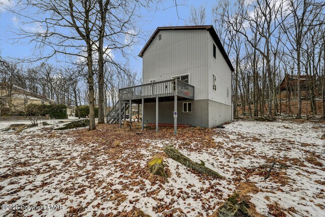 snow covered back of property featuring a wooden deck