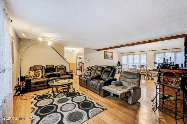 living room with vaulted ceiling, light hardwood / wood-style floors, and a textured ceiling