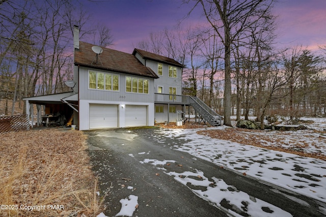 view of front facade with an attached garage, stairs, aphalt driveway, and a carport