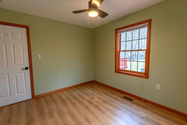 spare room with visible vents, a ceiling fan, light wood-style flooring, and baseboards