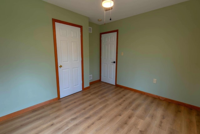 unfurnished bedroom with baseboards, light wood-type flooring, and visible vents