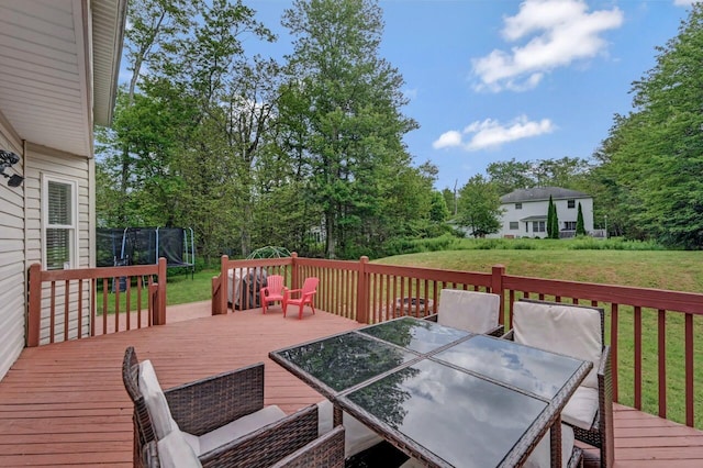 5117 Hounds Ear Rd, Tobyhanna, PA 18466 - deck featuring a trampoline, outdoor dining area, a yard, and view of scattered trees
