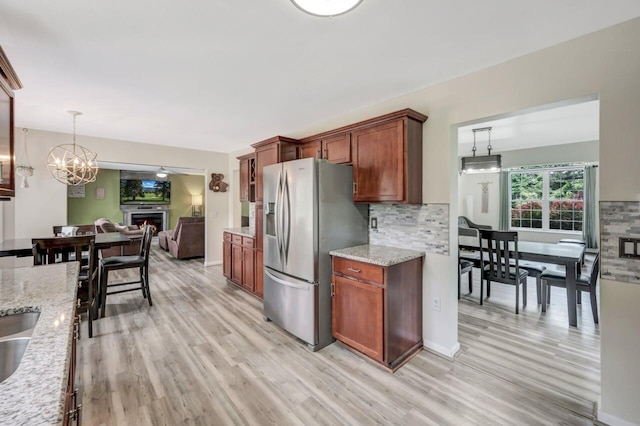 5117 Hounds Ear Rd, Tobyhanna, PA 18466 - kitchen featuring stainless steel fridge, light wood-style floors, decorative backsplash, light stone countertops, and a lit fireplace