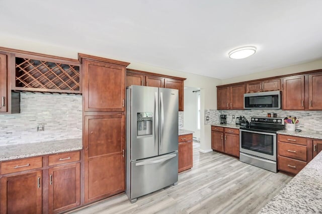 5117 Hounds Ear Rd, Tobyhanna, PA 18466 - kitchen featuring appliances with stainless steel finishes, decorative backsplash, light wood-style flooring, and light stone counters
