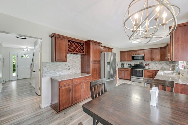 5117 Hounds Ear Rd, Tobyhanna, PA 18466 - kitchen featuring appliances with stainless steel finishes, a chandelier, tasteful backsplash, light wood-style floors, and light stone counters