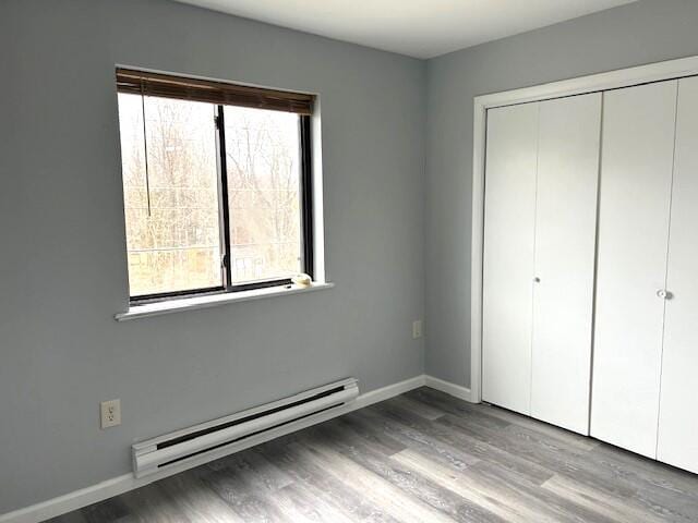 3073 Briarwood Dr, Tobyhanna, PA 18466 - unfurnished bedroom featuring a baseboard heating unit, multiple windows, wood finished floors, and a closet