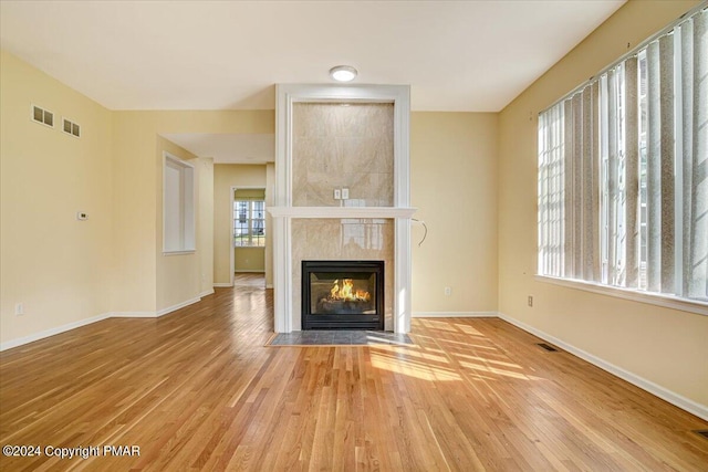 unfurnished living room with a tiled fireplace and light hardwood / wood-style floors