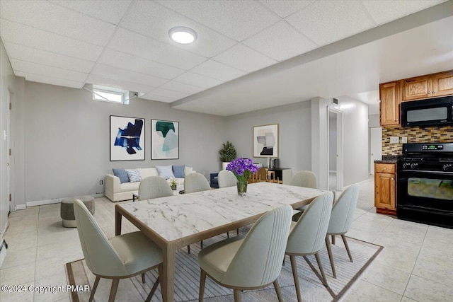 dining room with light tile patterned floors and a drop ceiling