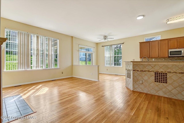 unfurnished living room featuring ceiling fan and light hardwood / wood-style flooring