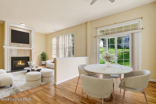 dining room with ceiling fan, a premium fireplace, and light hardwood / wood-style floors