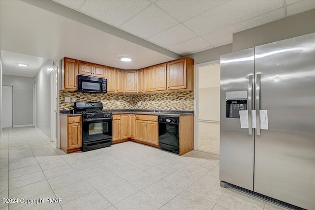 kitchen featuring tasteful backsplash, sink, light tile patterned floors, black appliances, and a drop ceiling