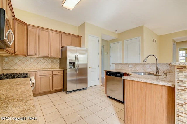 kitchen with sink, light stone counters, light tile patterned floors, appliances with stainless steel finishes, and decorative backsplash