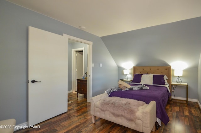 bedroom with vaulted ceiling, wood finished floors, and baseboards