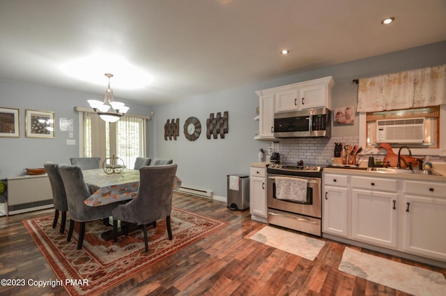 kitchen featuring dark wood finished floors, baseboard heating, appliances with stainless steel finishes, white cabinetry, and a sink