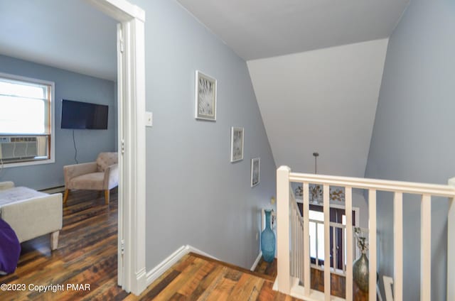 staircase featuring a baseboard radiator, baseboards, and wood finished floors