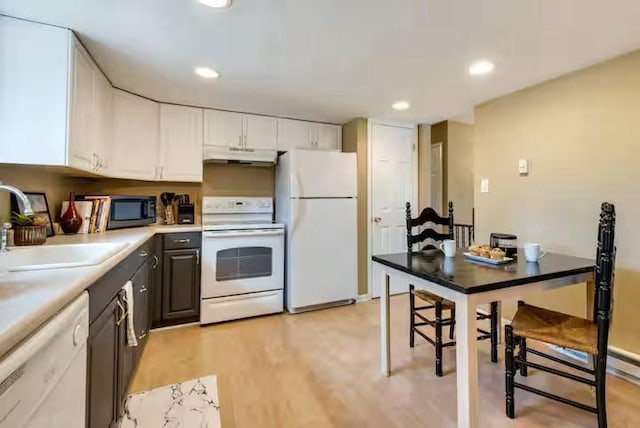 kitchen featuring light wood-style flooring, a sink, under cabinet range hood, recessed lighting, and white appliances