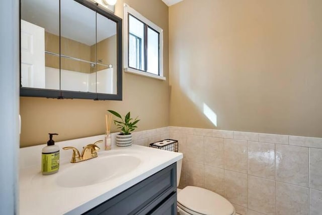 bathroom with toilet, tile walls, and vanity