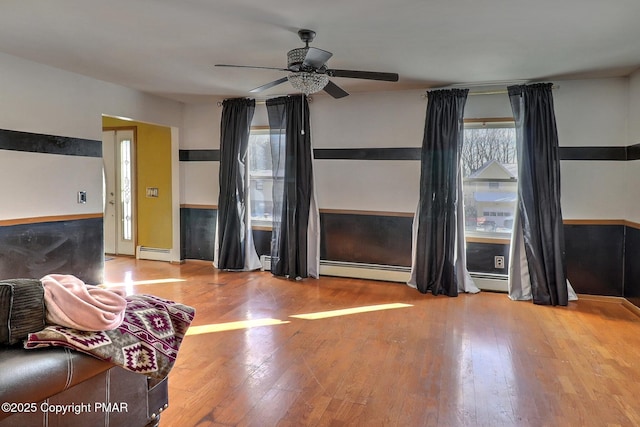 unfurnished living room with baseboard heating, ceiling fan, and hardwood / wood-style flooring