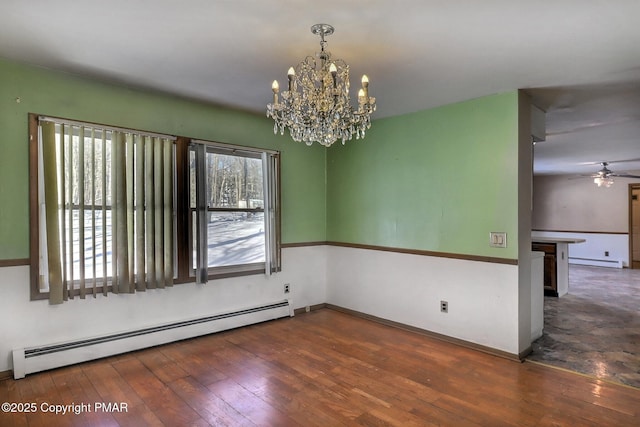 unfurnished room with dark hardwood / wood-style floors, ceiling fan with notable chandelier, and a baseboard heating unit