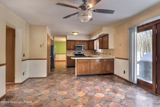 kitchen featuring ceiling fan, appliances with stainless steel finishes, kitchen peninsula, and sink