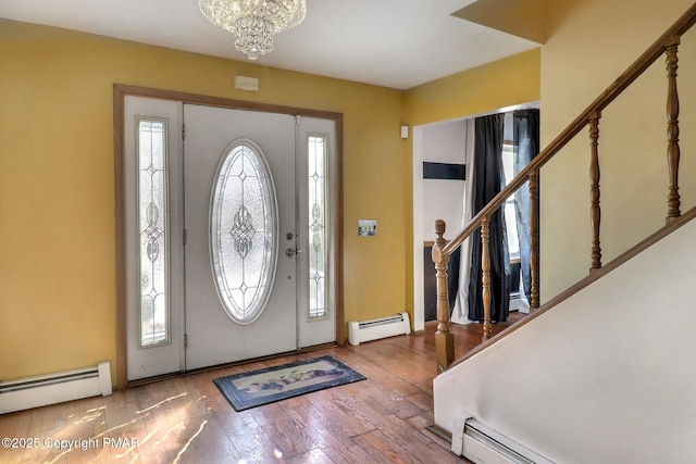 foyer entrance with a baseboard radiator, wood-type flooring, and a chandelier