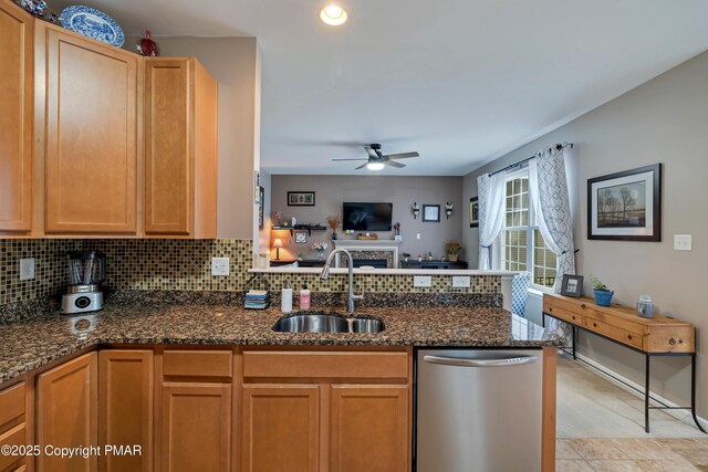 kitchen featuring tasteful backsplash, dark stone countertops, sink, and stainless steel dishwasher