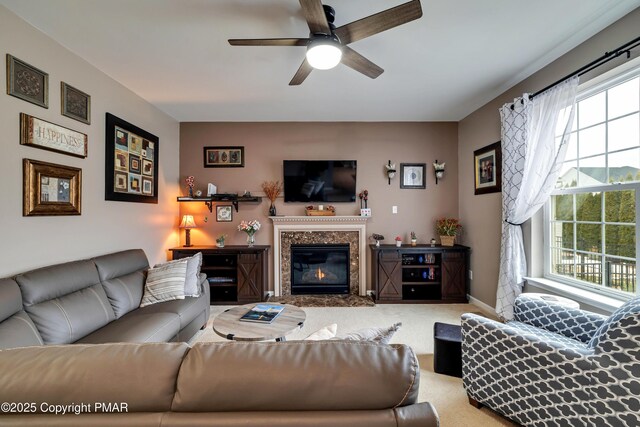 carpeted living room featuring ceiling fan and a high end fireplace