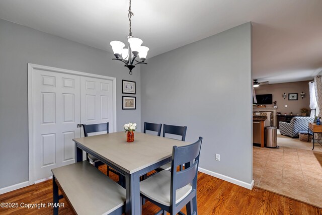 dining space with ceiling fan with notable chandelier and wood-type flooring