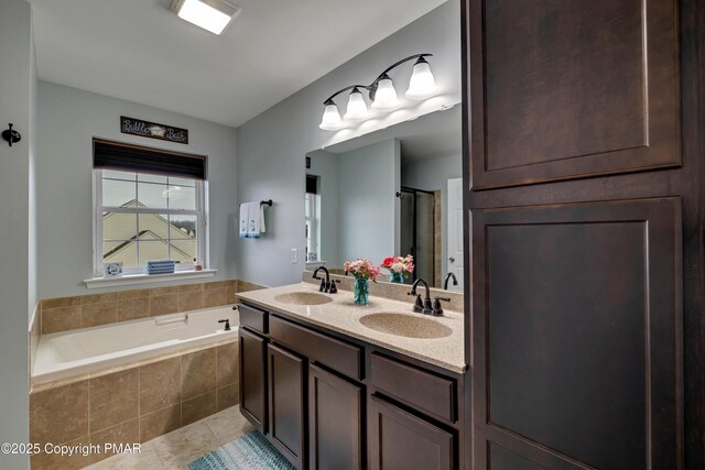 bathroom with a relaxing tiled tub, vanity, and tile patterned flooring