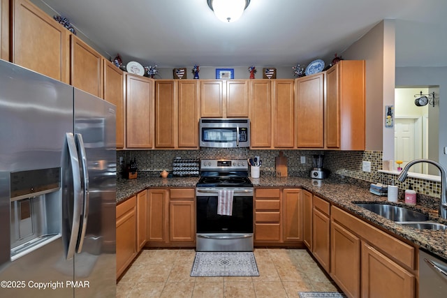 kitchen featuring stainless steel appliances, tasteful backsplash, sink, and dark stone countertops