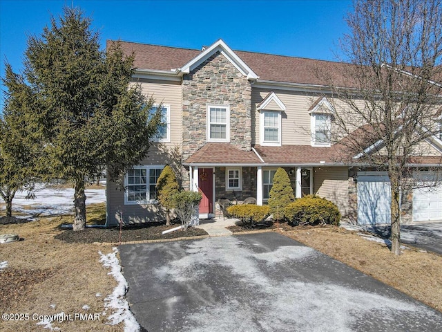 multi unit property featuring a garage, stone siding, aphalt driveway, and a shingled roof