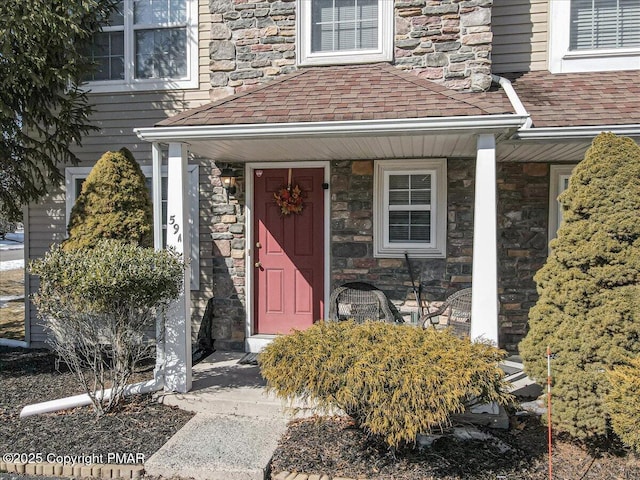 property entrance featuring stone siding, a shingled roof, and a porch