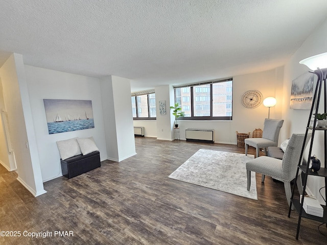 living room featuring a textured ceiling, dark wood finished floors, and baseboards