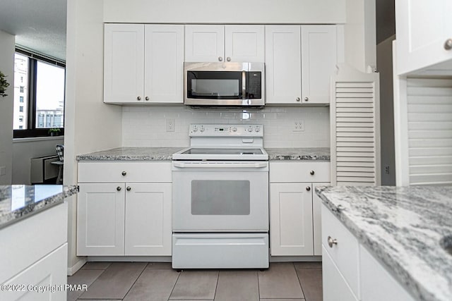 kitchen featuring light tile patterned flooring, white electric range, white cabinets, backsplash, and stainless steel microwave