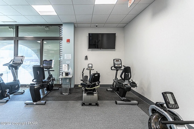 workout area featuring a drop ceiling and baseboards