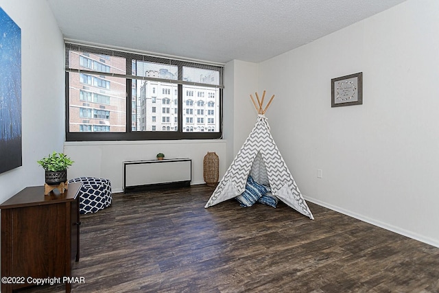 rec room featuring a textured ceiling, wood finished floors, and baseboards