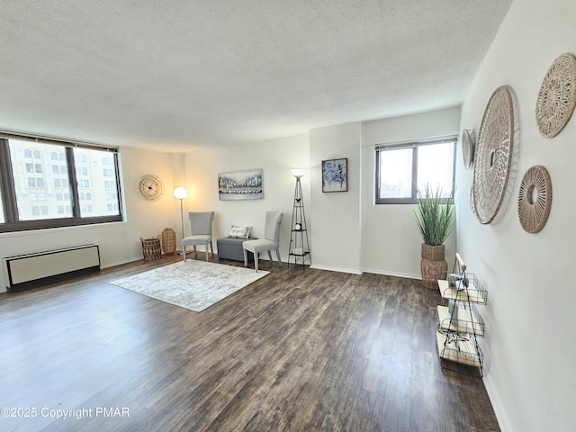 unfurnished living room with dark wood-type flooring, radiator heating unit, and a textured ceiling