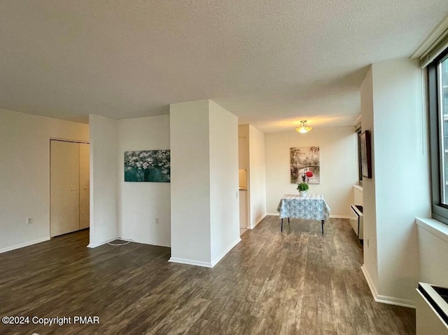 hallway featuring a textured ceiling, wood finished floors, and baseboards