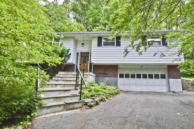 207 Shepard Ave, Delaware Water Gap, PA 18327 - split foyer home featuring an attached garage, brick siding, and asphalt driveway