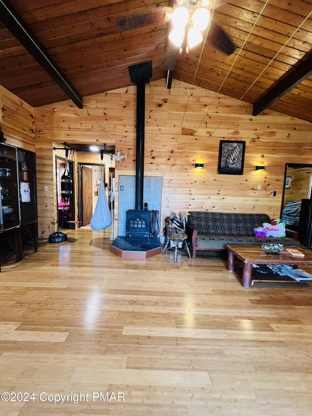 214 Mockingbird Ct, Bushkill, PA 18324 - unfurnished living room featuring wood walls, wood finished floors, a wood stove, a ceiling fan, and lofted ceiling with beams