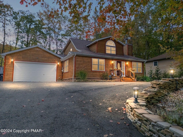 view of front of home featuring a garage, aphalt driveway, log veneer siding, and a chimney