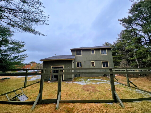 back of property with a lawn and fence