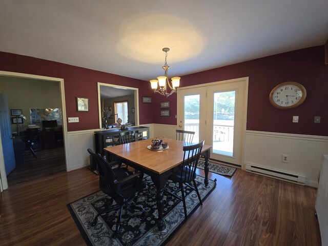 dining space with dark wood-type flooring, a chandelier, a wainscoted wall, and baseboard heating