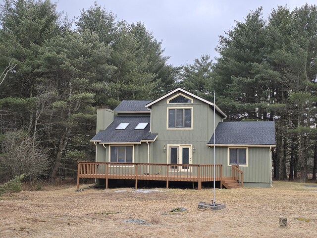 view of front of property featuring french doors, a chimney, a shingled roof, and a wooden deck