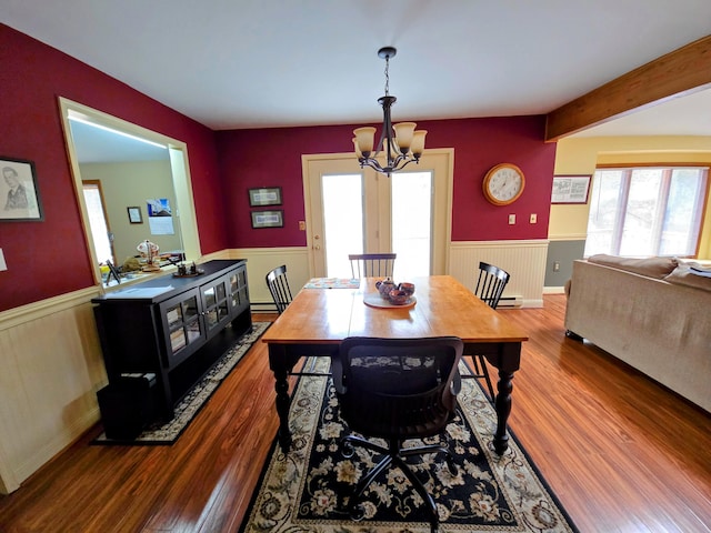 dining area featuring a wainscoted wall, beam ceiling, wood finished floors, and an inviting chandelier