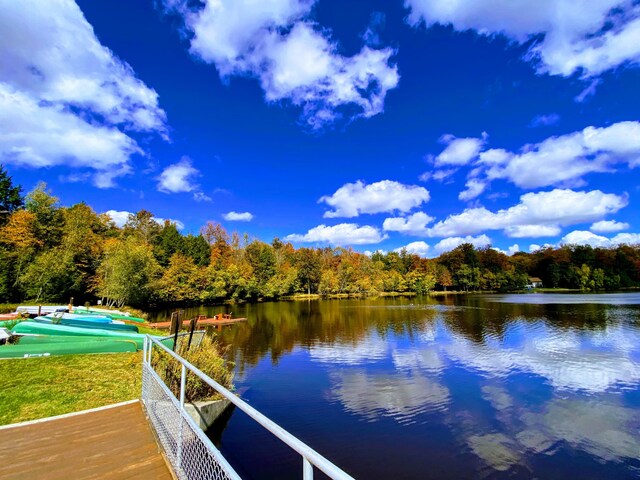 view of dock featuring a pool, a water view, and a forest view