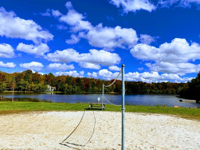 surrounding community featuring volleyball court, a water view, and a view of trees